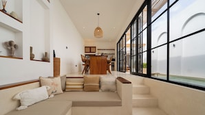 A modern interior with a sofa, staircase, and a dining area. - Villa Bellora by Pertama Stay (Seminyak)