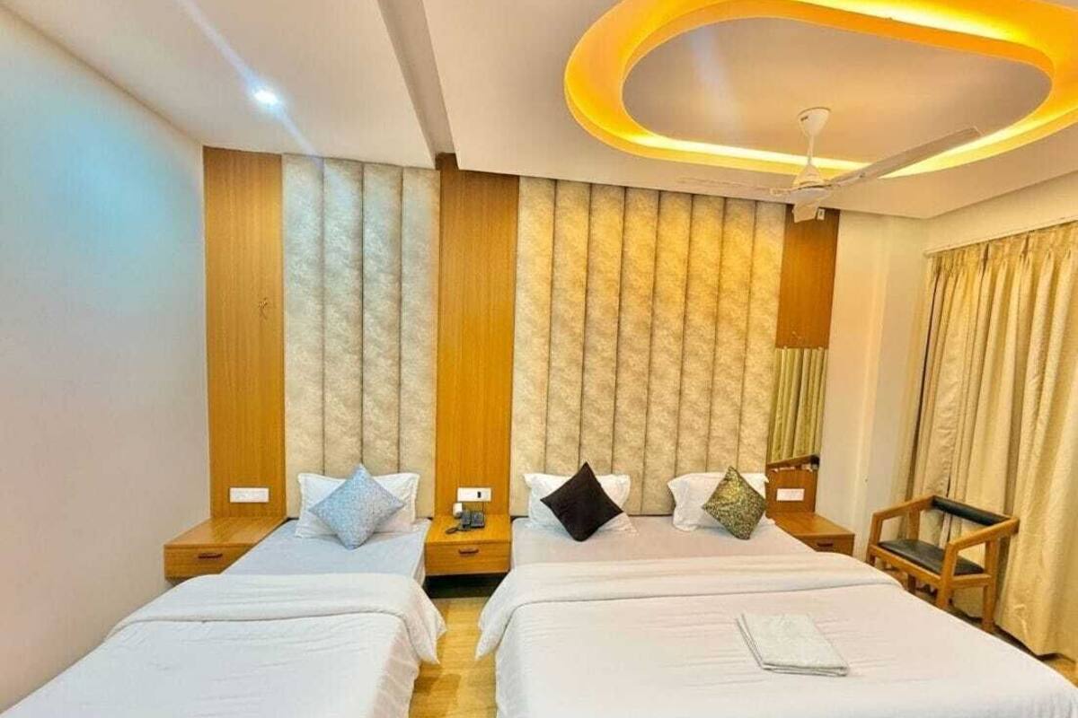 A hotel room with two beds, a wooden headboard, a ceiling light fixture, and a chair.