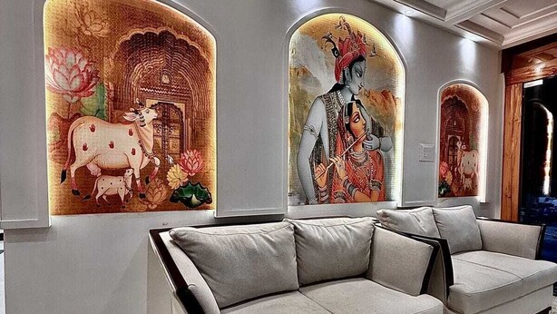 Eine moderne Lobby mit einer Couch, einer Decke mit eingelassener Beleuchtung und einer Wand mit Wandgemälde.