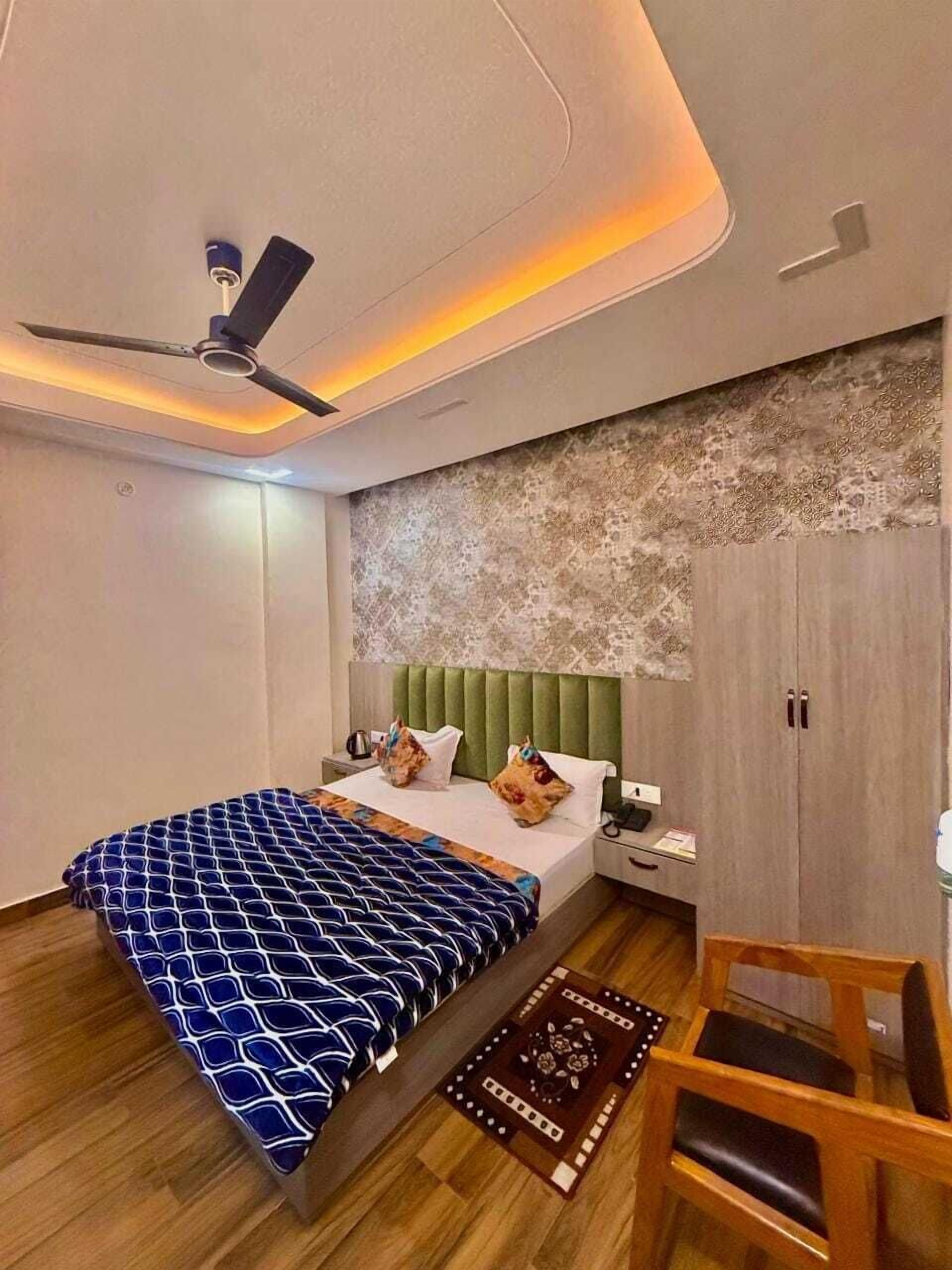 A modern bedroom with a bed, a chair, a wardrobe, and a ceiling fan.