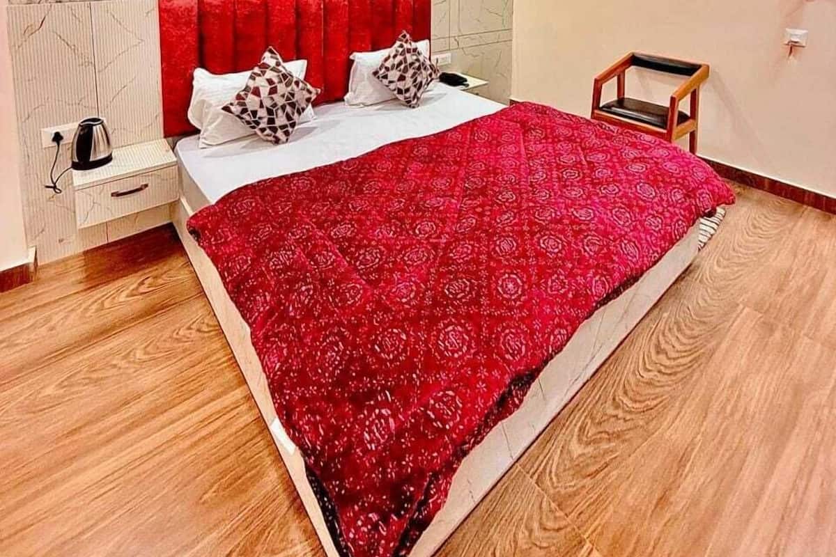 A bedroom with a bed, a nightstand, a chair, a ceiling fan, and a textured wall.