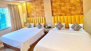 Ein Hotelzimmer mit zwei Betten, einem Deckenventilator, einem Fenster mit Vorhängen und einer strukturierten Wand.