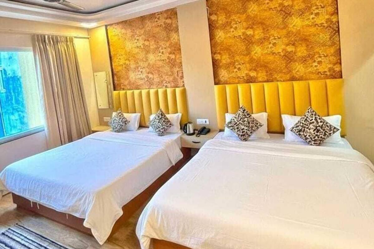 A hotel room with two beds, a ceiling fan, a window with curtains, and a textured wall.