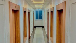 Ein Hotelgang mit Holztüren, einem Marmorboden und einer Decke mit eingelassener Beleuchtung.
