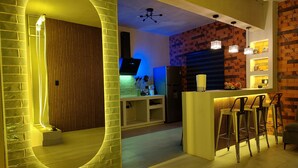 A modern kitchen with a built-in oven, a refrigerator, and a bar area with stools.