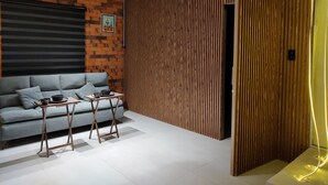 A modern living room with a sofa, a coffee table, and a wooden partition wall.