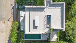 Eine Vogelperspektive eines modernen Gebäudes mit Pool auf dem Dach, einer Treppe und umliegender Bepflanzung.