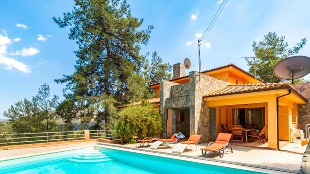 Zona piscina con lettini e un edificio in pietra con tetto in tegole.