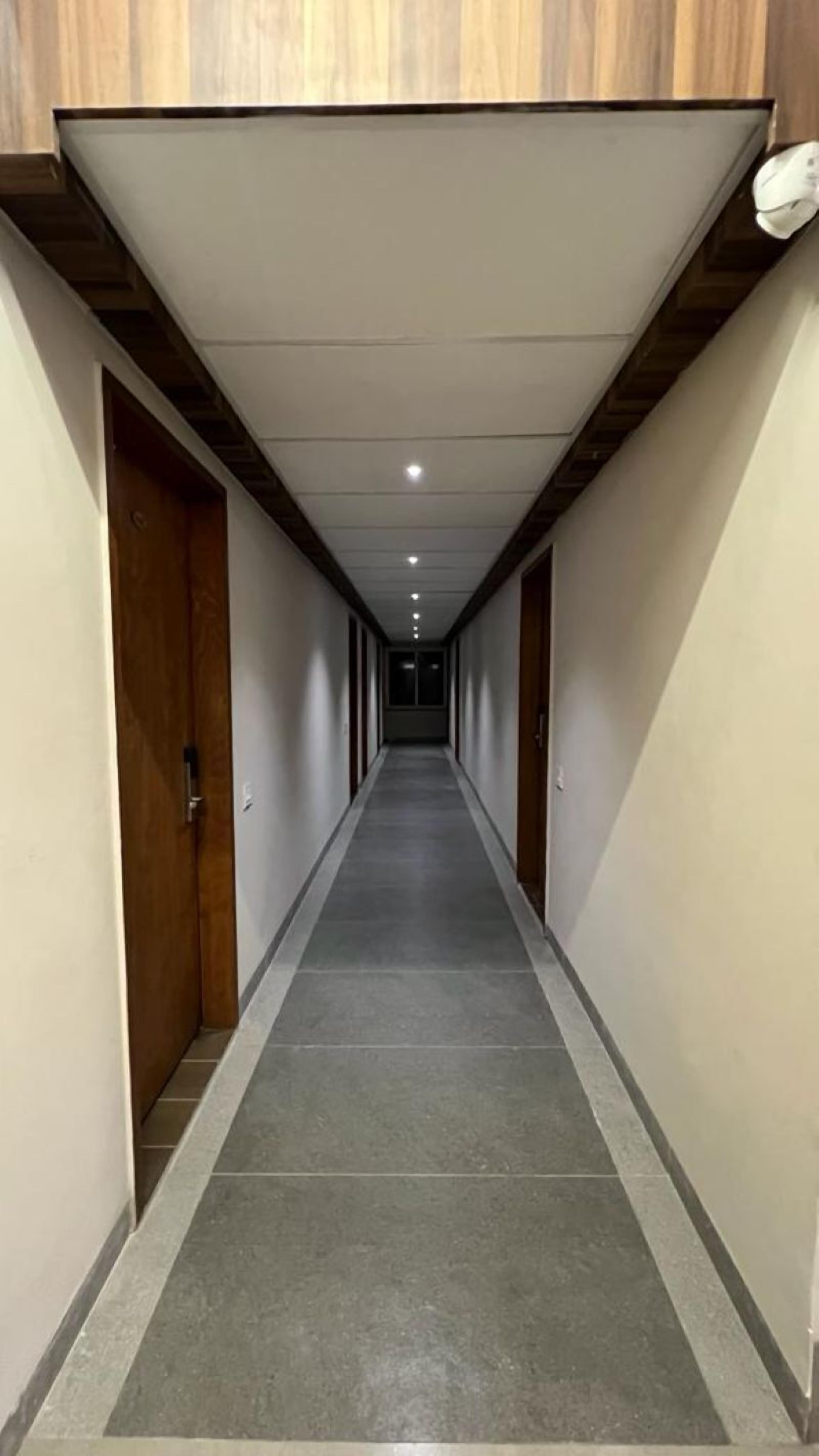 A long, narrow hallway with wooden doors on either side and a tiled floor.