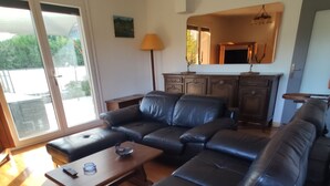 A living room with a sectional sofa, a coffee table, and a lamp. There is a sliding glass door leading to an outdoor area. - Apartment with private terrace, in the country and in the city at the same time. (Privas)