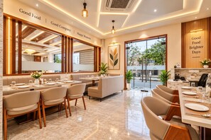 Un restaurant au décor moderne, avec une longue table à manger, des sièges confortables et une vue sur l’extérieur.
