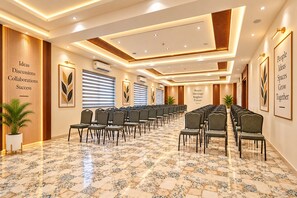 Un salón de conferencias con filas de sillas, un suelo estampado y obras de arte enmarcadas en las paredes.