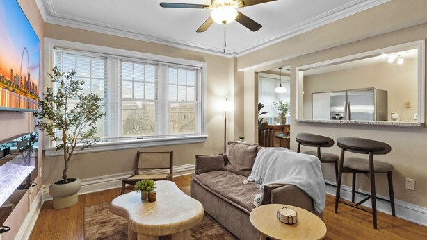 A living room with a sofa, two chairs, a small table, a ceiling fan, and a large window with blinds. - Cozy 1BR Retreat in Central West End with Fireplace, Sofa Bed & City Views (St. Louis)