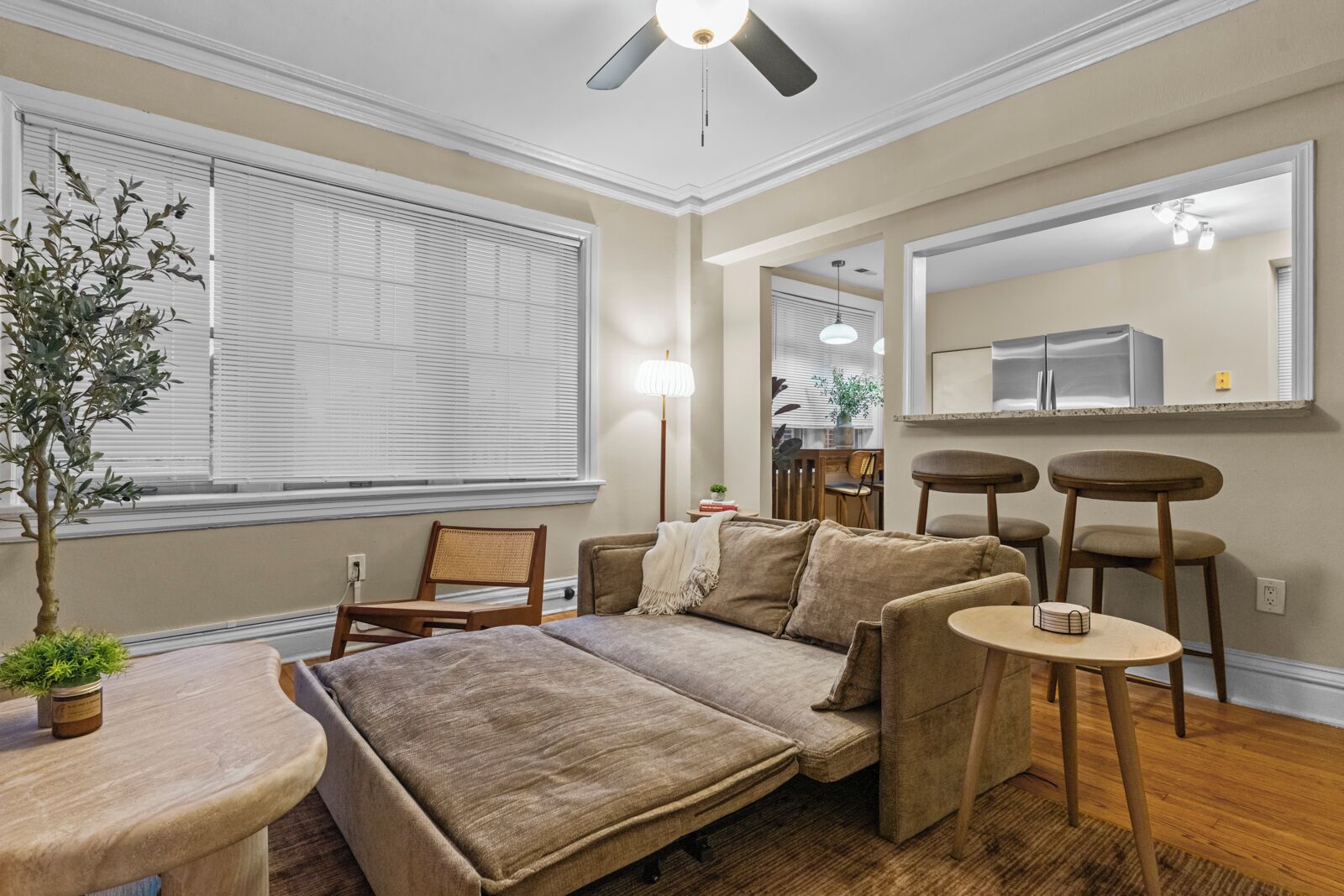 A cozy living room with a sofa, chairs, a small table, and a potted plant.