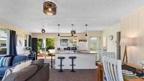 Een moderne keuken met een centraal eiland, barstoelen en hanglampen.