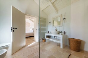 A modern bathroom with a glass shower door, a white sink, and a large mirror. - Masseria Maranna Trulli & Spa (Martina Franca)