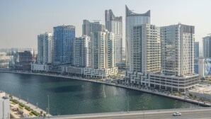 Un quartier urbain caractérisé par de grands immeubles, une architecture moderne, une promenade en bord de mer et une rue très fréquentée.
