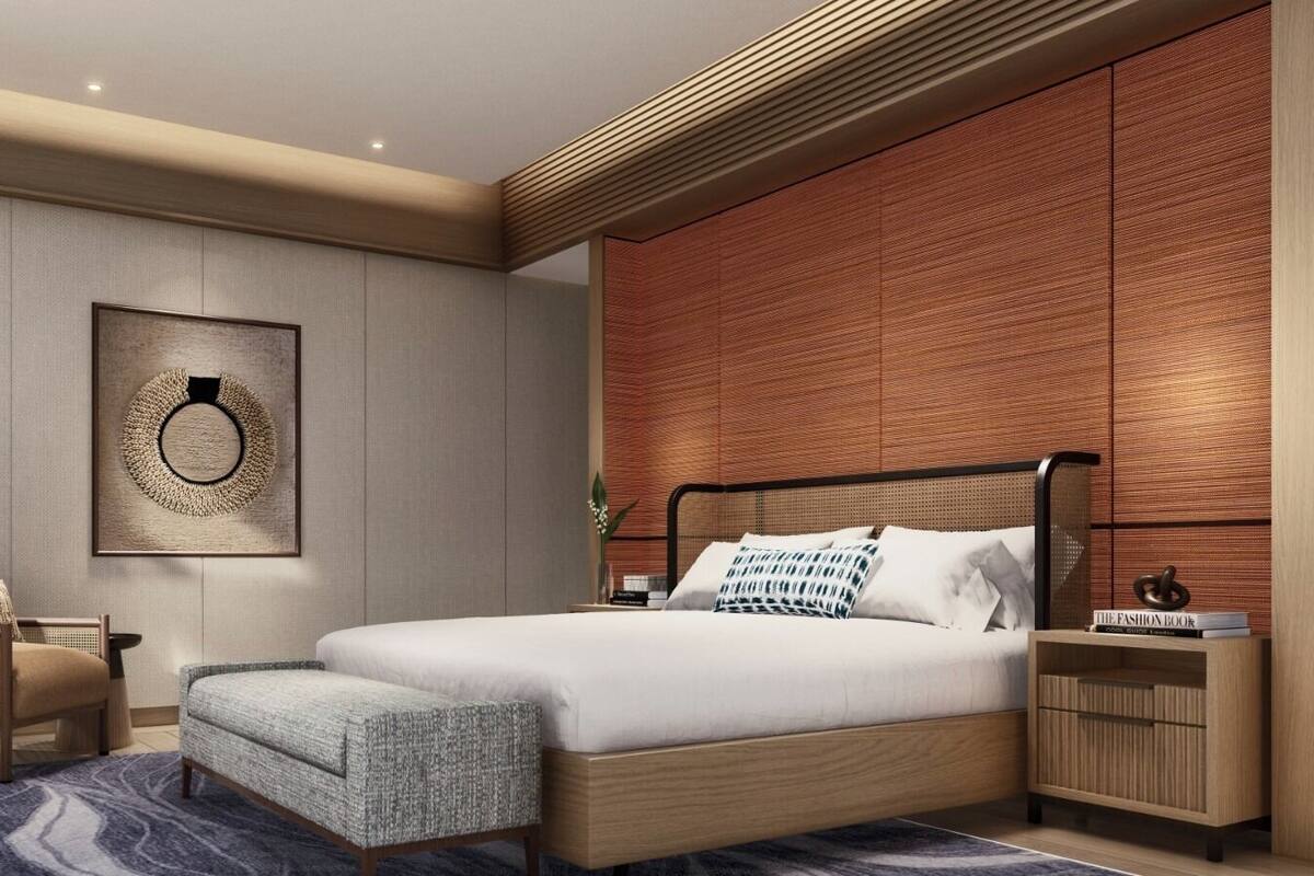 Une chambre à coucher moderne, avec un lit, des tables de chevet, une chaise, une lampe et une œuvre d’art accrochée au mur.