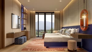 A modern bedroom with a large bed, a TV, a desk, and a view of mountains through the window. - Kaban Hotel & Casino Boracay (Boracay Island)