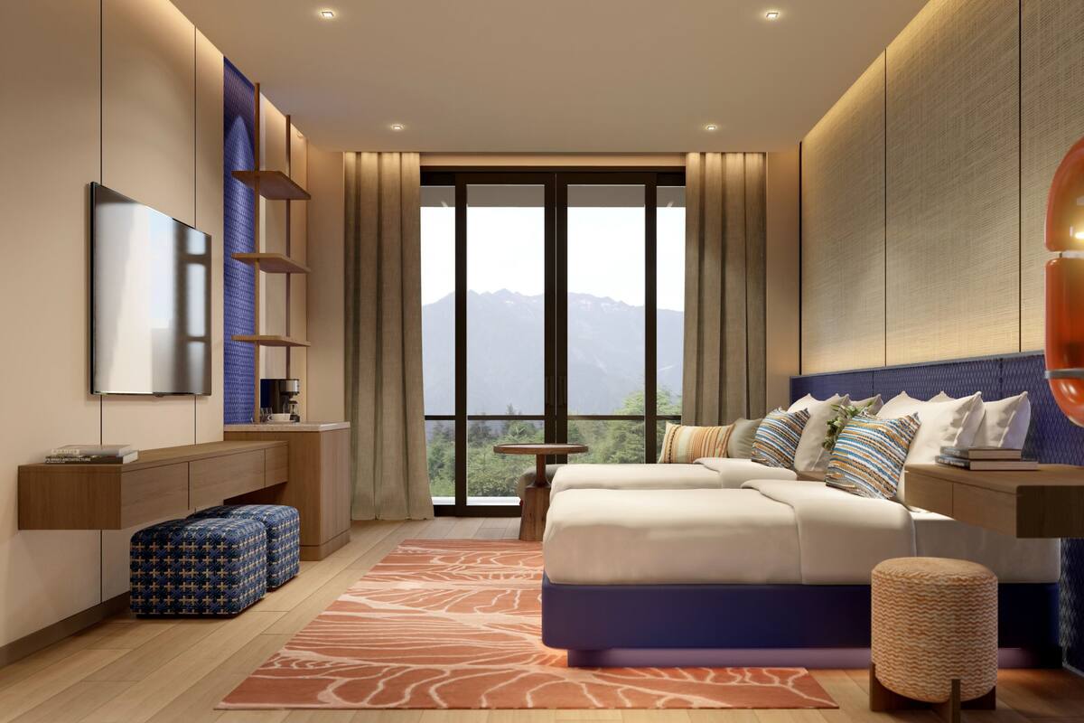 Une chambre moderne avec un grand lit, une télévision, un bureau et une vue sur les montagnes par la fenêtre.