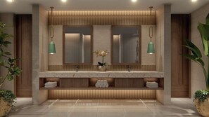 Ein modernes Badezimmer mit einem Holzkosmetikschrank, zwei Spiegeln und grünen Pendelleuchten.