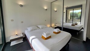 Habitación de hotel moderna con una cama grande, una mesita de noche, un espejo y vistas al exterior.