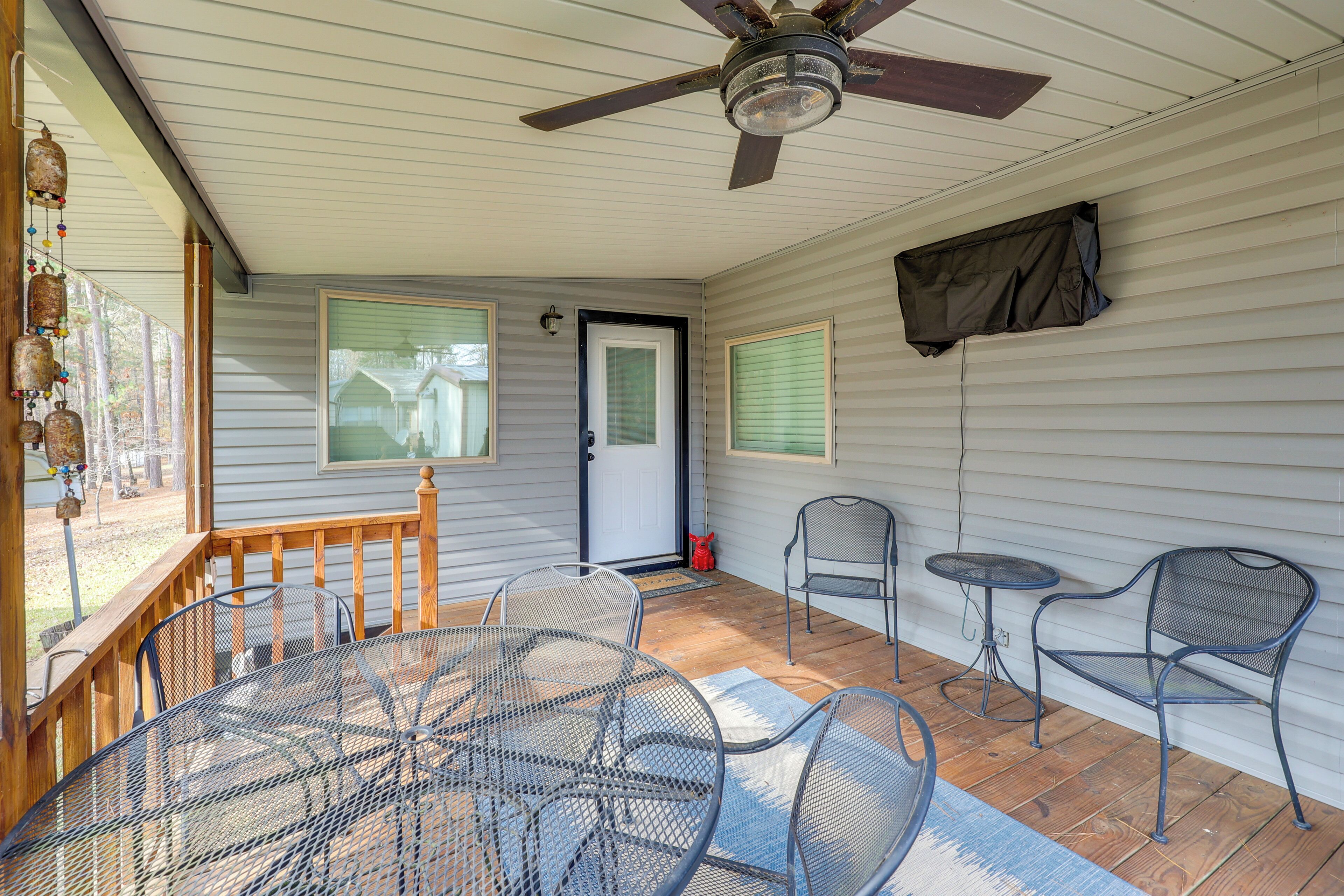Une terrasse couverte avec une table et des chaises, un ventilateur de plafond et une porte.