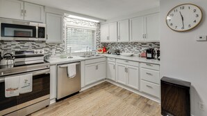 A modern kitchen with white cabinets, a microwave, an oven, a dishwasher, and a clock on the wall. - Bring Your Boat: Family Home Steps to Lake Greeson (Kirby)