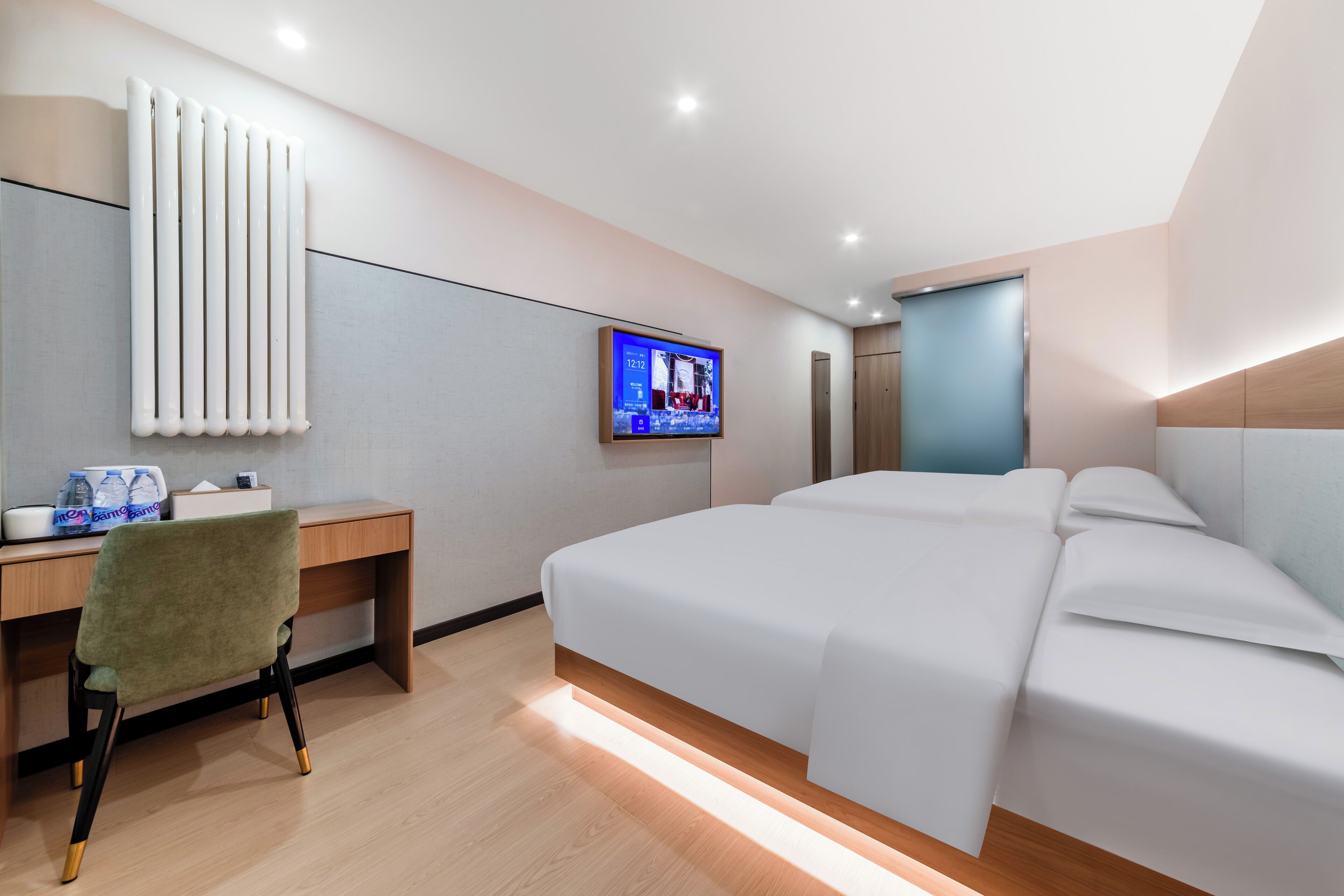 A modern hotel room with a large bed, a desk with a chair, a television, and a radiator.
