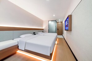 Ein modernes Hotelzimmer mit einem großen Bett, Nachttischen, einem an der Wand montierten Fernseher und Holzboden.