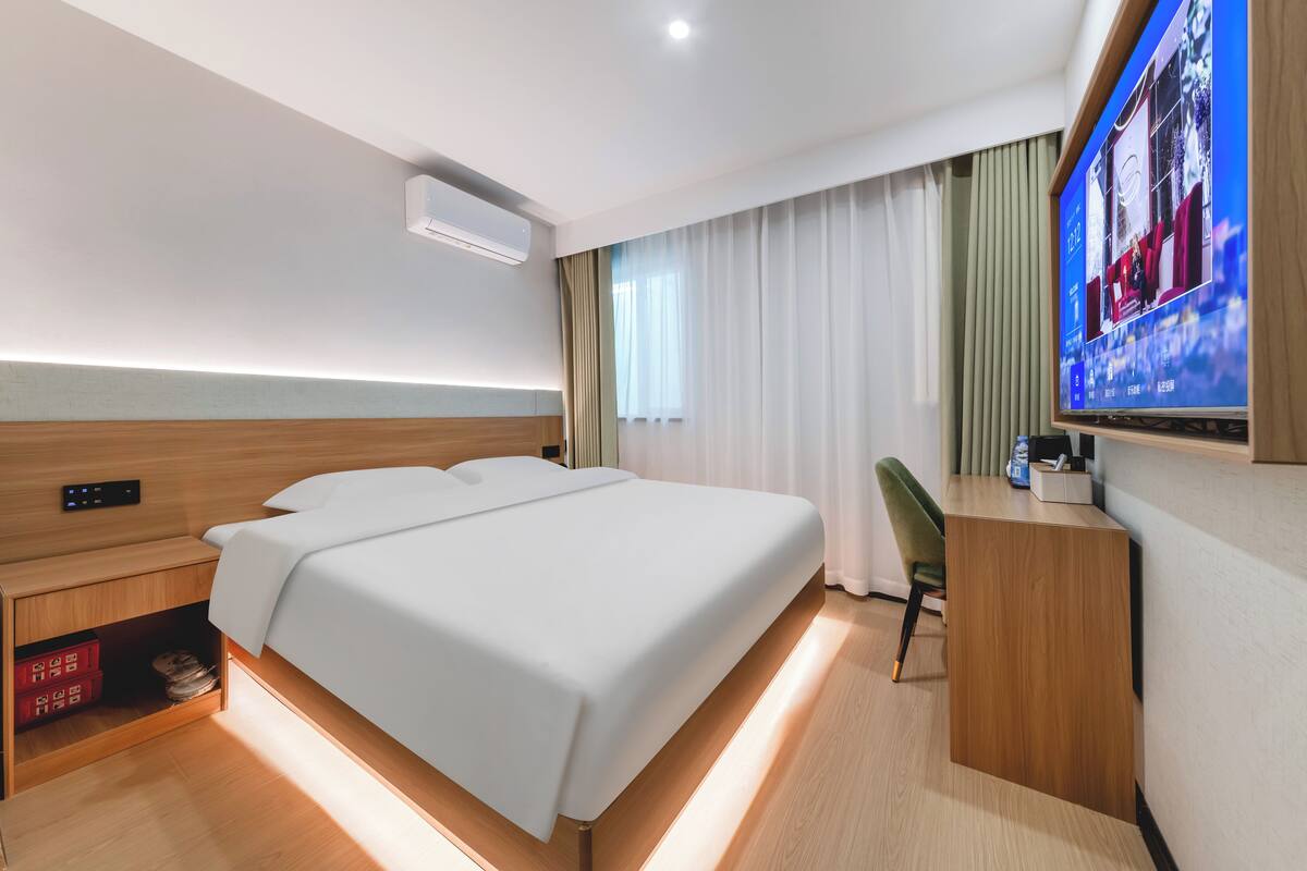 Een moderne hotelkamer met een bed, bureau en televisie.