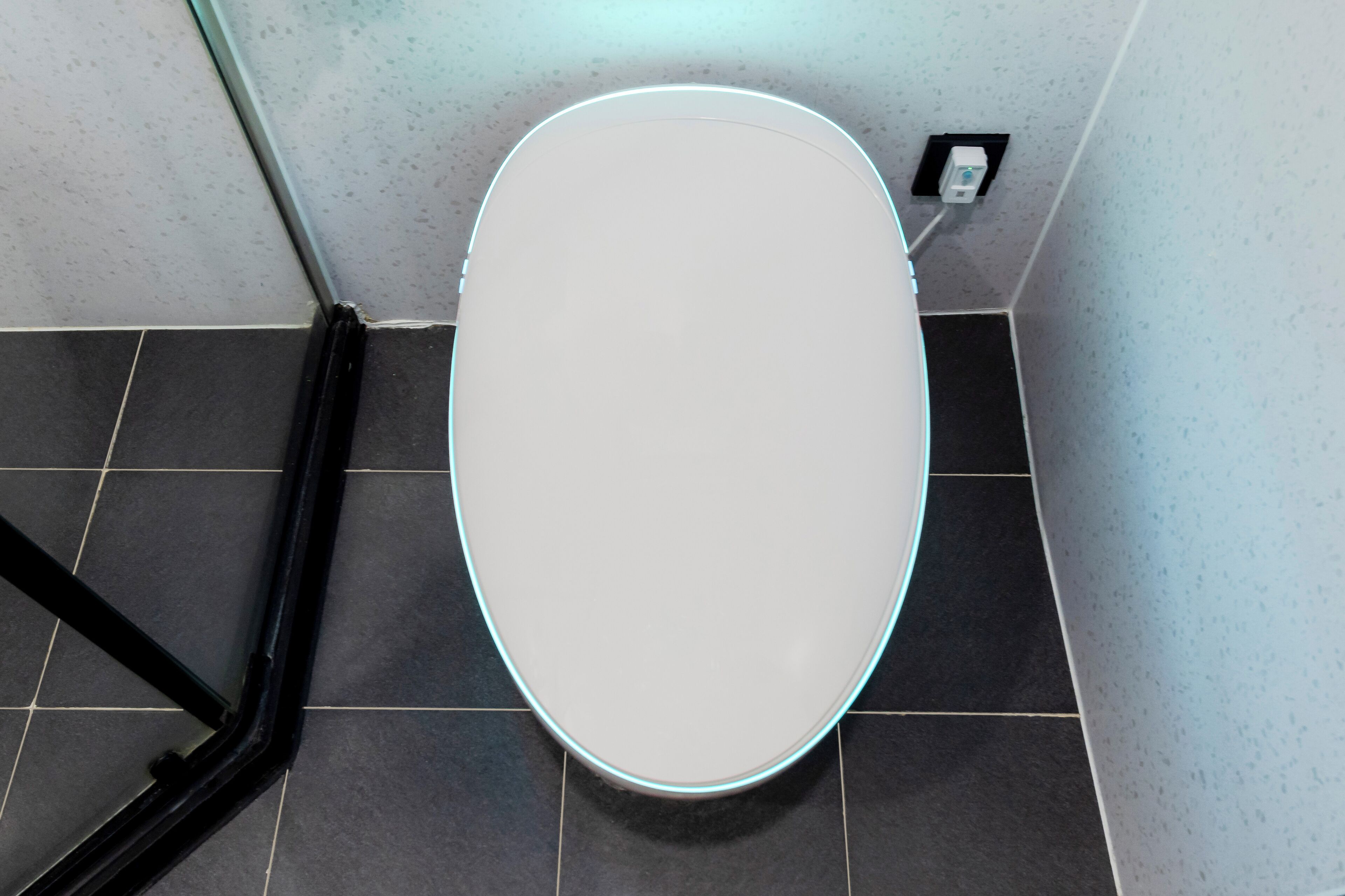 Une salle de bain moderne avec des toilettes blanches, un cadre noir et un sol carrelé.