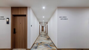 A hotel hallway with a wooden door, a digital keypad, and a patterned carpet. - Anyi (Beijing)