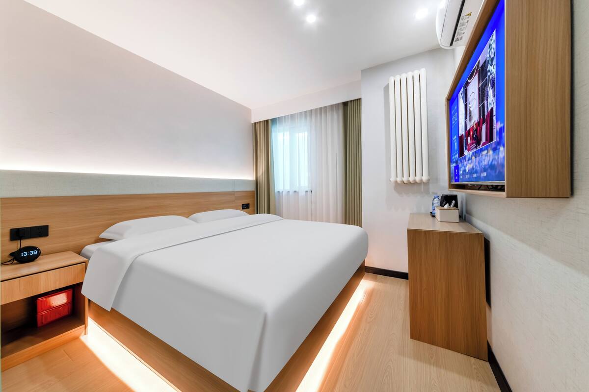 Een moderne hotelkamer met een groot bed, nachtkastjes, een televisie en een ingebouwde kachel.