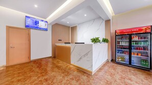 A reception area with a marble counter, a digital screen, and a refrigerated beverage display. - Anyi (Beijing)