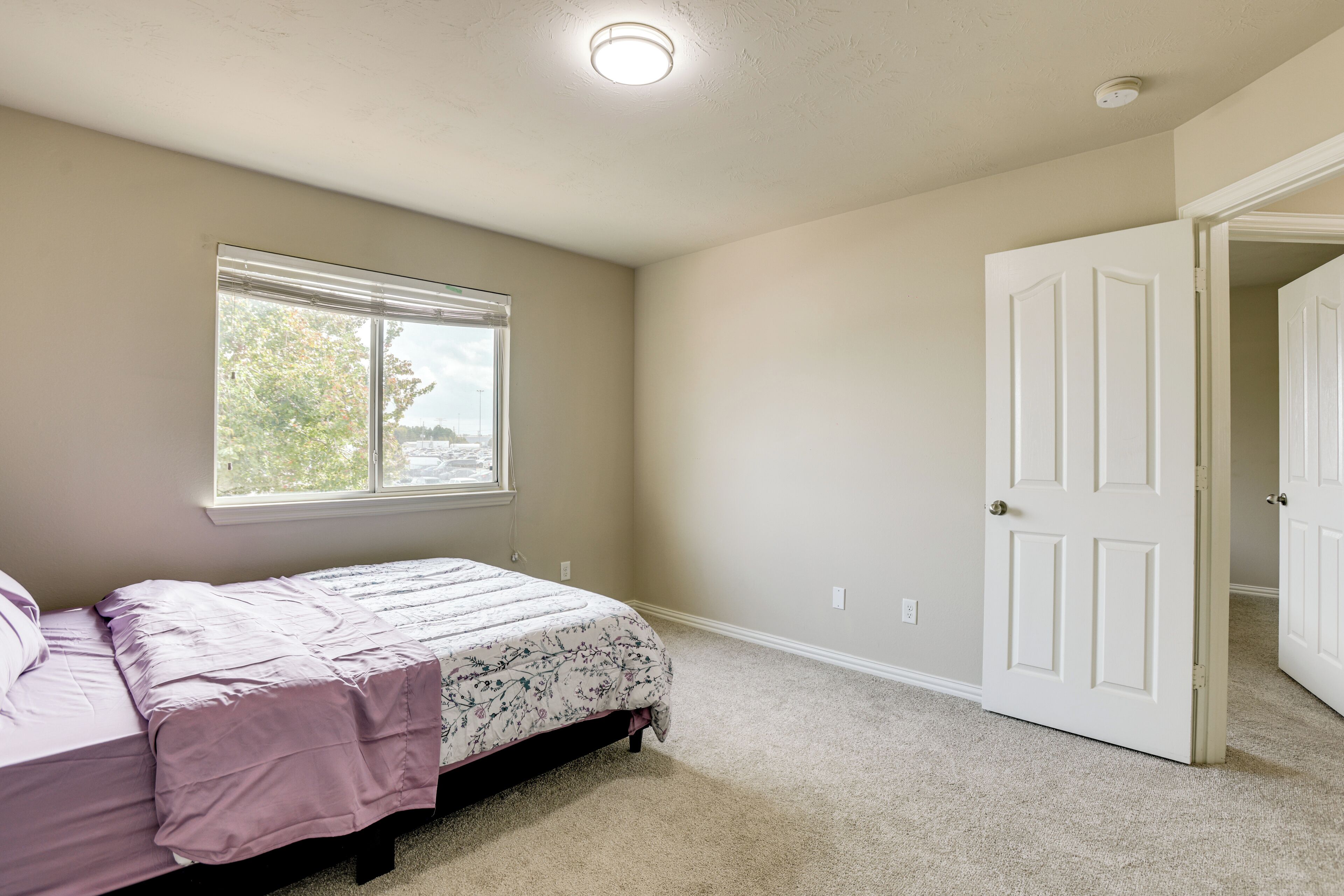 Un dormitorio con cama, ventana y puerta.
