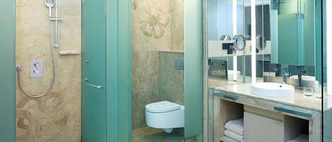 Un baño moderno con ducha envuelta en vidrio, un inodoro blanco y un tocador con un espejo grande.