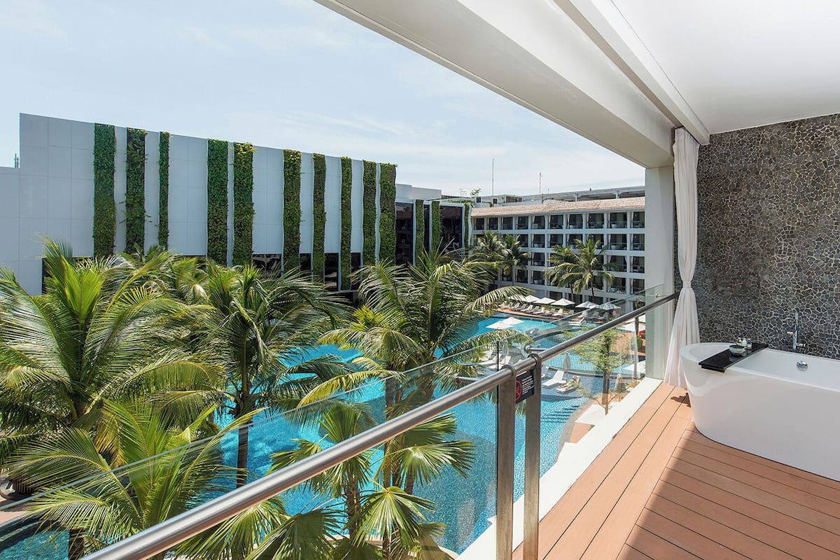 Un balcon offrant une vue sur une piscine, un jacuzzi et un bâtiment moderne agrémenté de jardins verticaux.