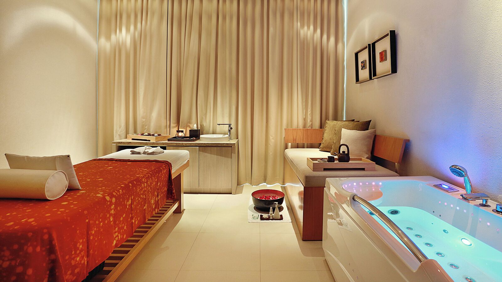 A hotel room with two beds, a sitting area, a bathtub, and a desk with a computer.