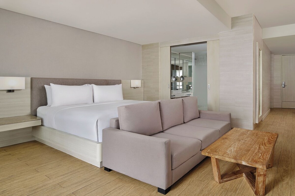 Une chambre d’hôtel moderne équipée d’un lit, d’un canapé, d’une table en bois et d’un petit coin repas.