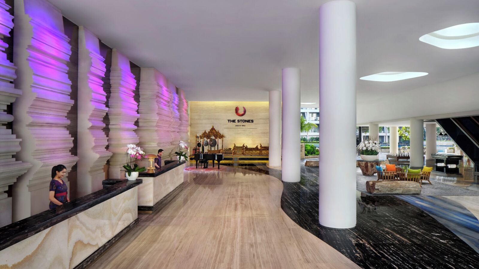 Um saguão de hotel com uma mesa de recepção, um piano e um mural grande na parede.