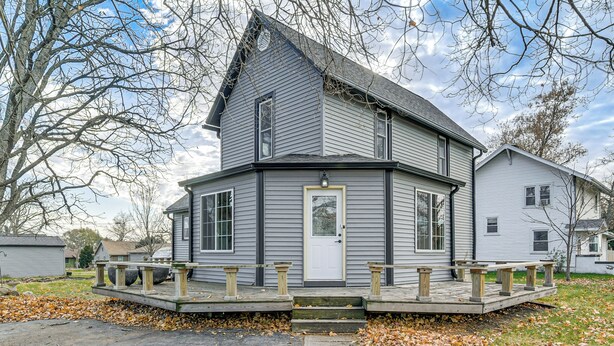 Une maison à deux étages avec un porche à l’avant et un garage.