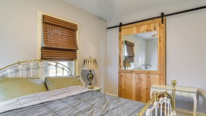 Une chambre à coucher comprenant un lit, une table de chevet, une lampe, une commode en bois et un miroir.