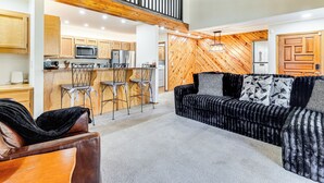 Ein großzügiger Wohnbereich mit hoher Decke, einer Holztreppe und einer Küche mit modernen Geräten.