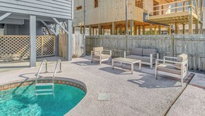 Piscina con escalera, rodeada de mobiliario exterior y una terraza de madera.