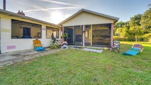 A house with a covered porch, a sliding glass door, and a small garden area with a lawn and two lawn chairs.