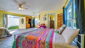 A spacious bedroom with a large bed, a ceiling fan, and a view of the outside.