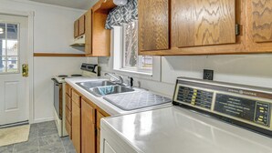 Una cocina con armarios de madera, un lavamanos de acero inoxidable, una estufa y un horno General Electric.