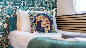 A bed with a white pillow, a leopard print pillow, and a green blanket. - Pontypool Haven Retreat - 3Bedroom Flat (Torfaen Principal Area)