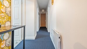 A narrow hallway with patterned wallpaper, a table with a phone, and a radiator. - Pontypool Haven Retreat - 3Bedroom Flat (Torfaen Principal Area)